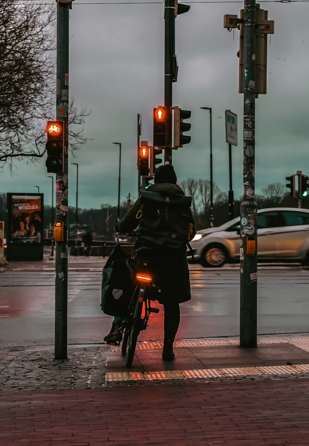 um homem andando de bicicleta por uma rua próxima a semáforos
