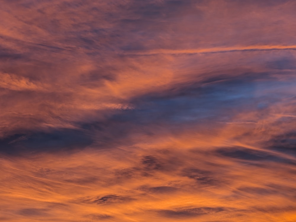 a plane flying in the sky at sunset