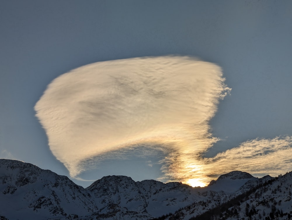 a large cloud in the sky over a mountain