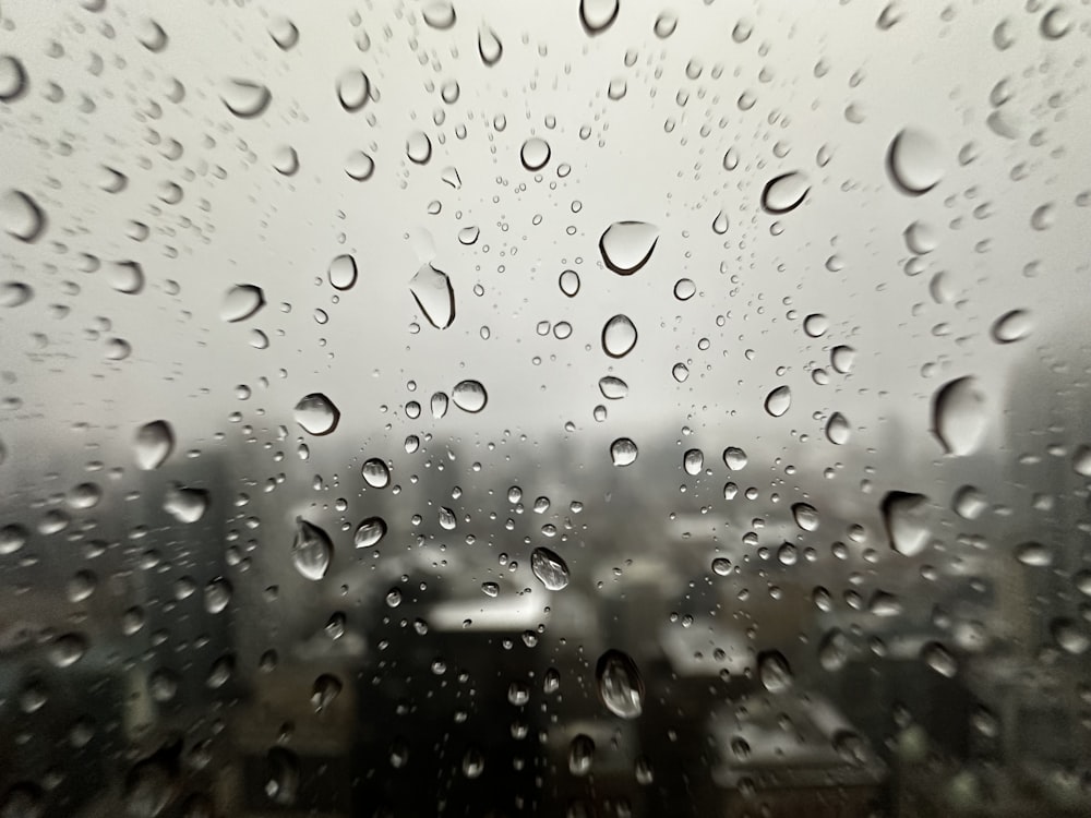 Regentropfen auf einem Fenster mit einer Stadt im Hintergrund