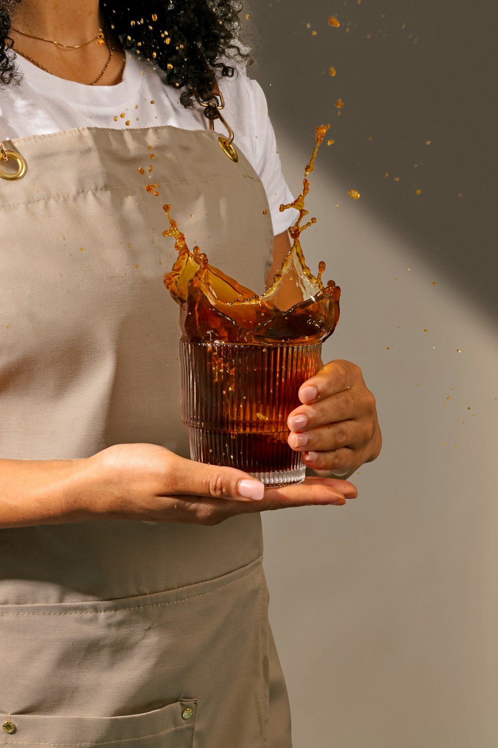 a woman in an apron holding a glass of liquid