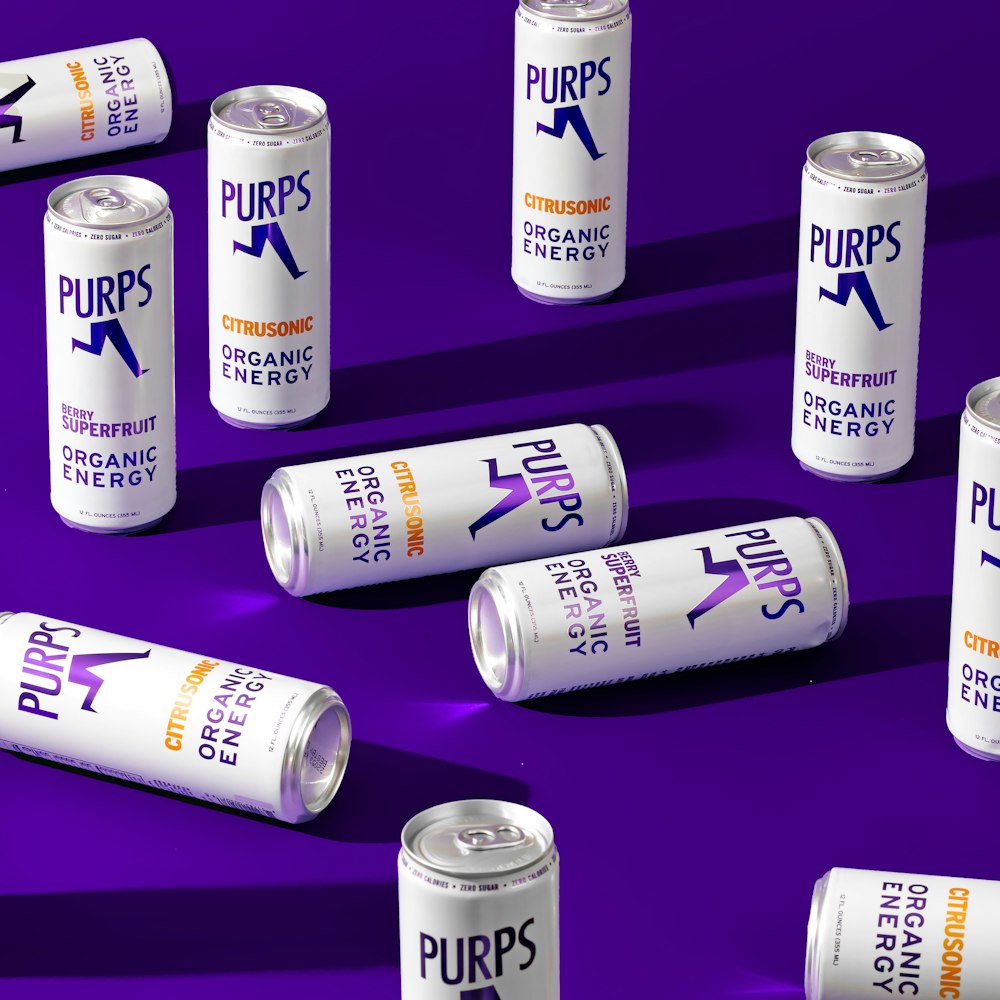 six cans of pures energy drink on a purple background