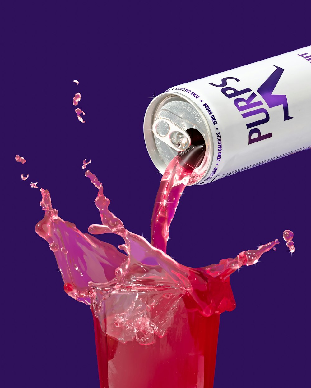 a can of pink soda being poured into a glass