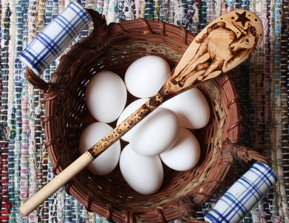 a basket filled with white eggs and a wooden spoon
