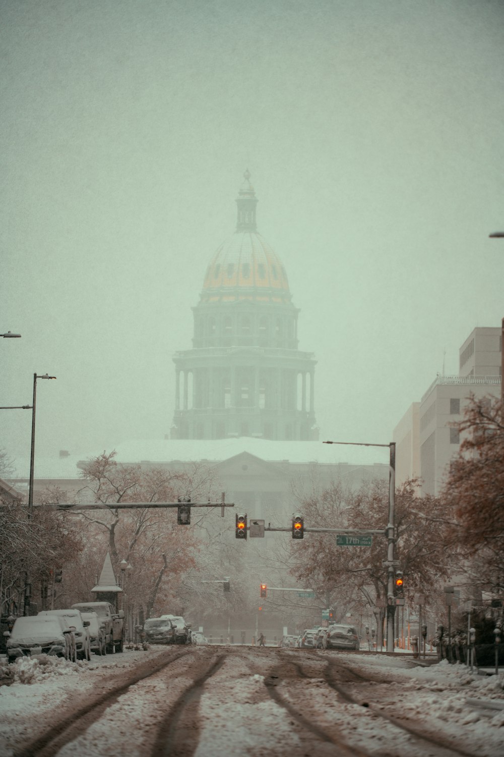 a snowy street with a traffic light and a building in the background