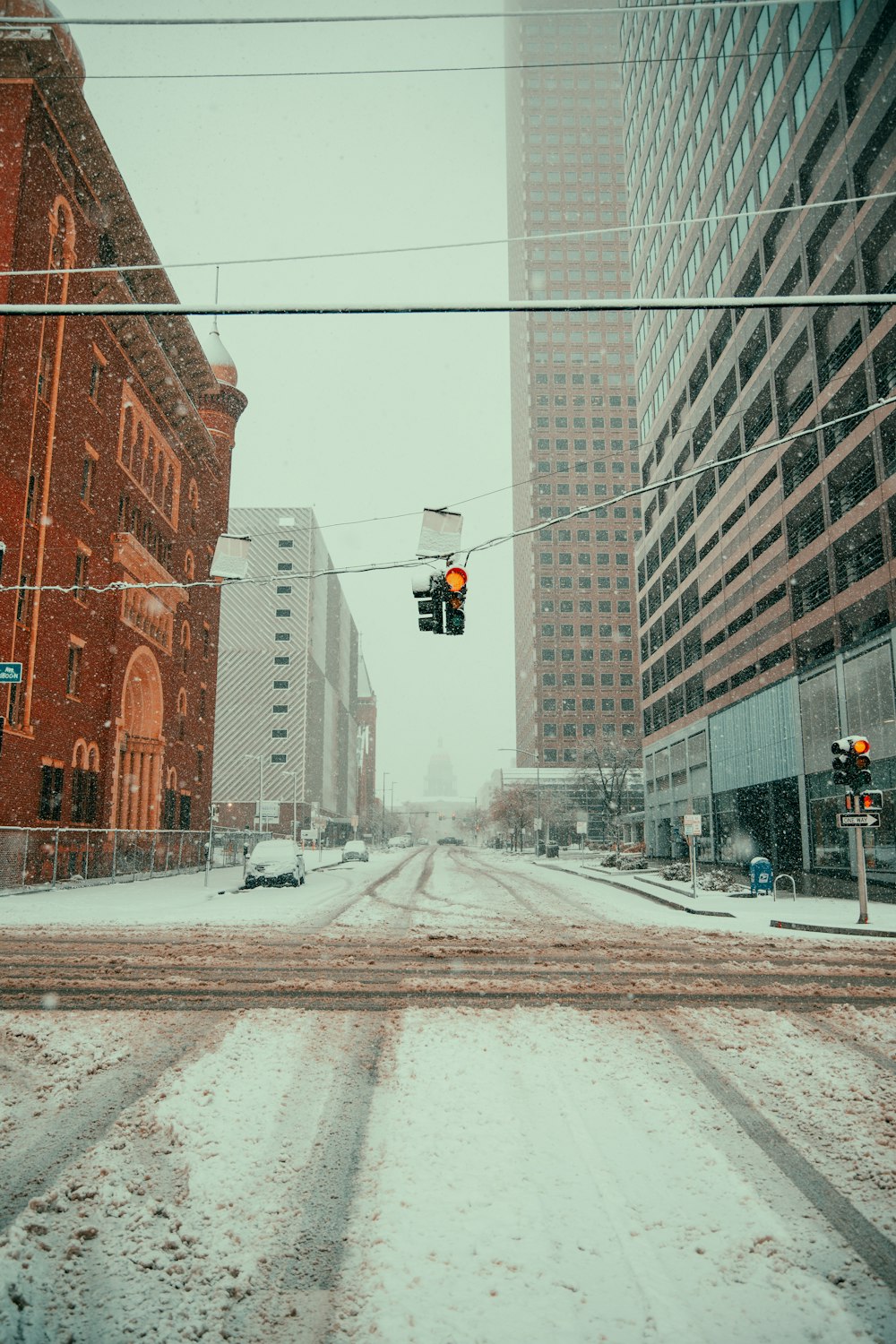 a snowy street with traffic lights and buildings