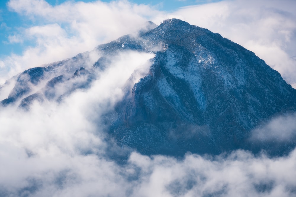 a mountain covered in clouds under a blue sky