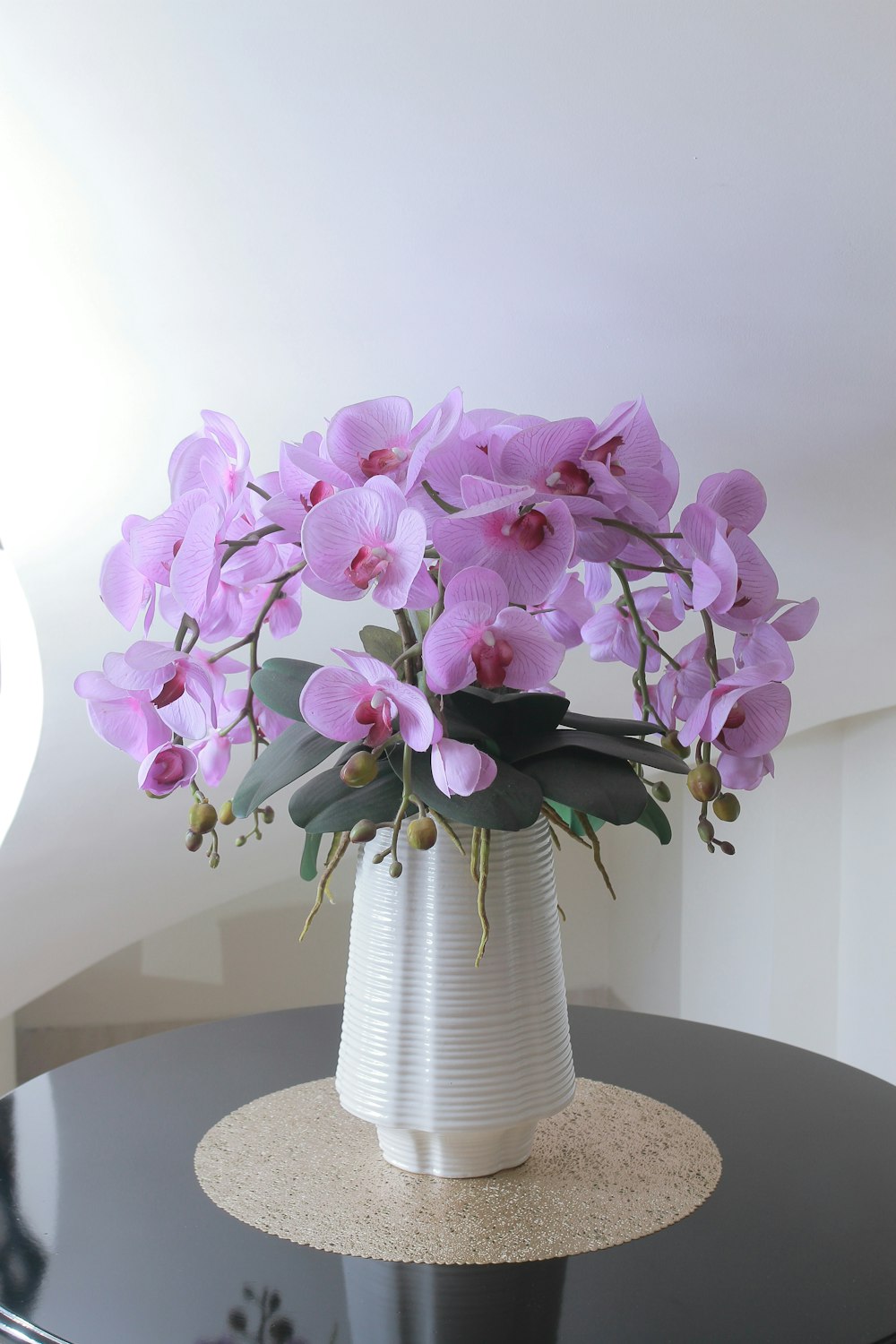 a white vase filled with purple flowers on top of a table