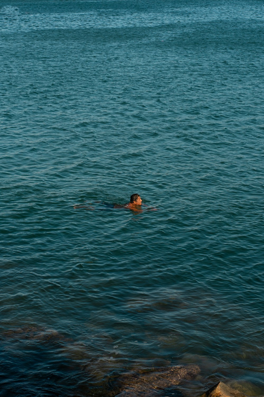 a person swimming in the ocean with a boat in the background