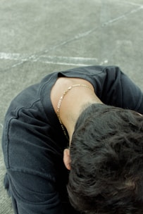 a man with a chain around his neck sitting on the ground