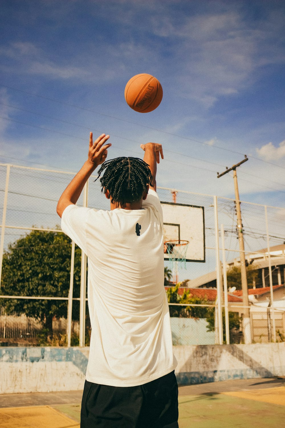 a man in white shirt and black shorts playing with a basketball