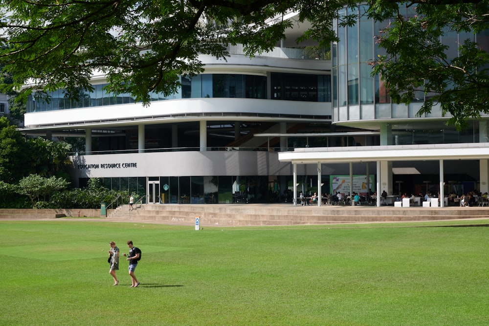 a couple of people walking across a lush green field