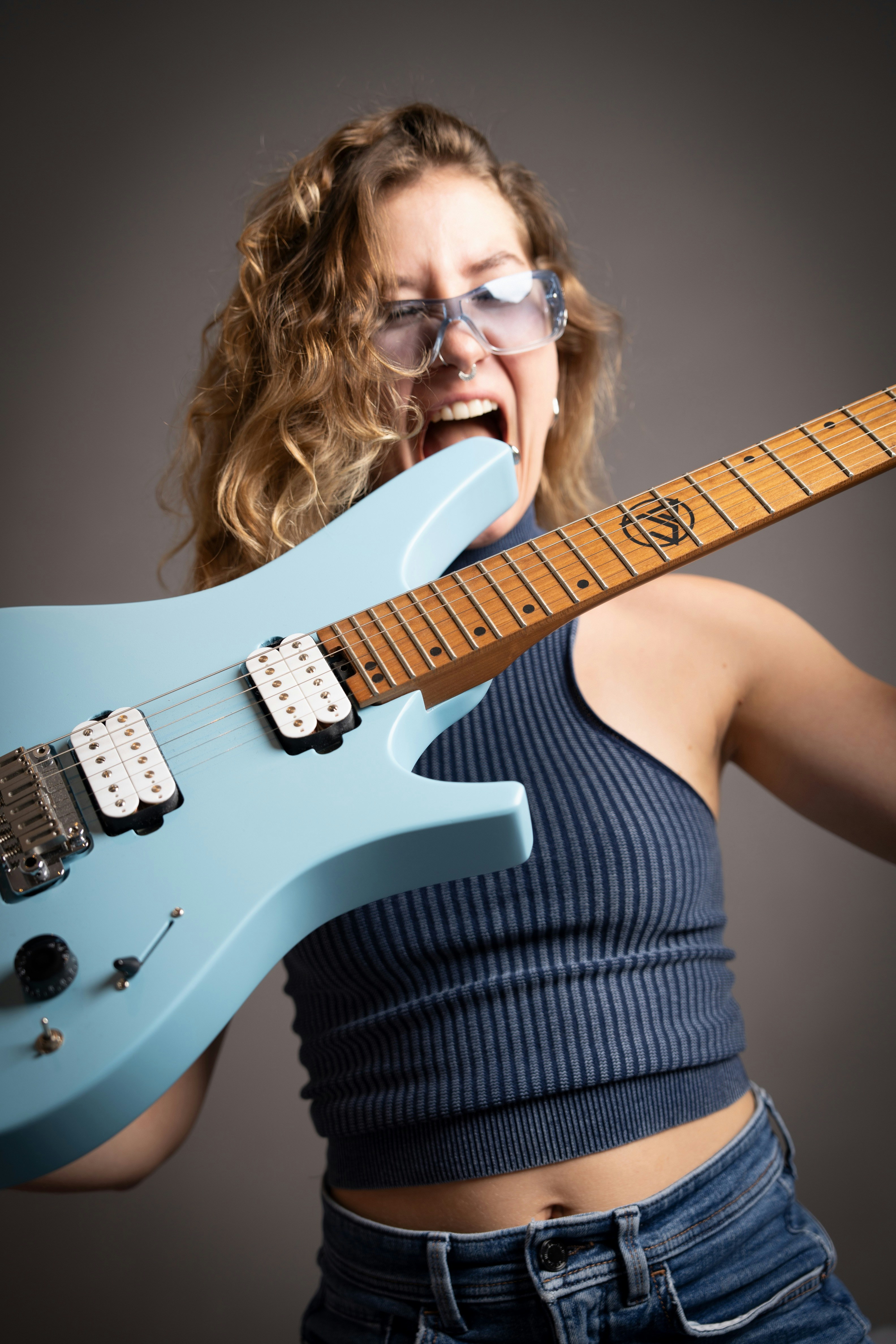 uma mulher com óculos segurando uma guitarra azul