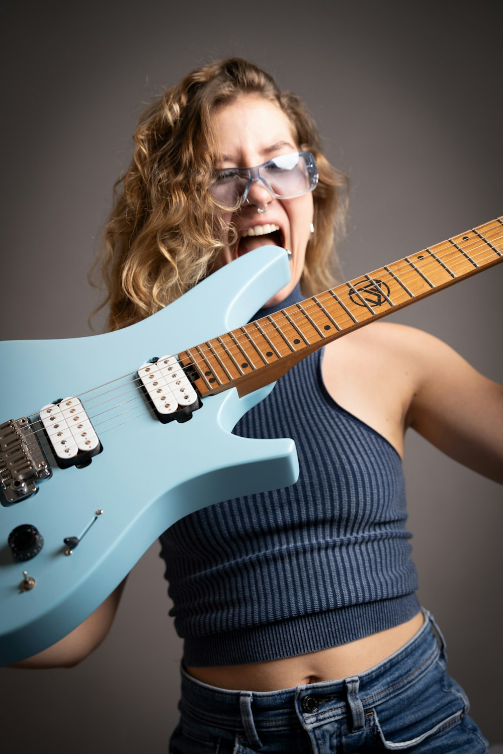 a woman with glasses holding a blue guitar