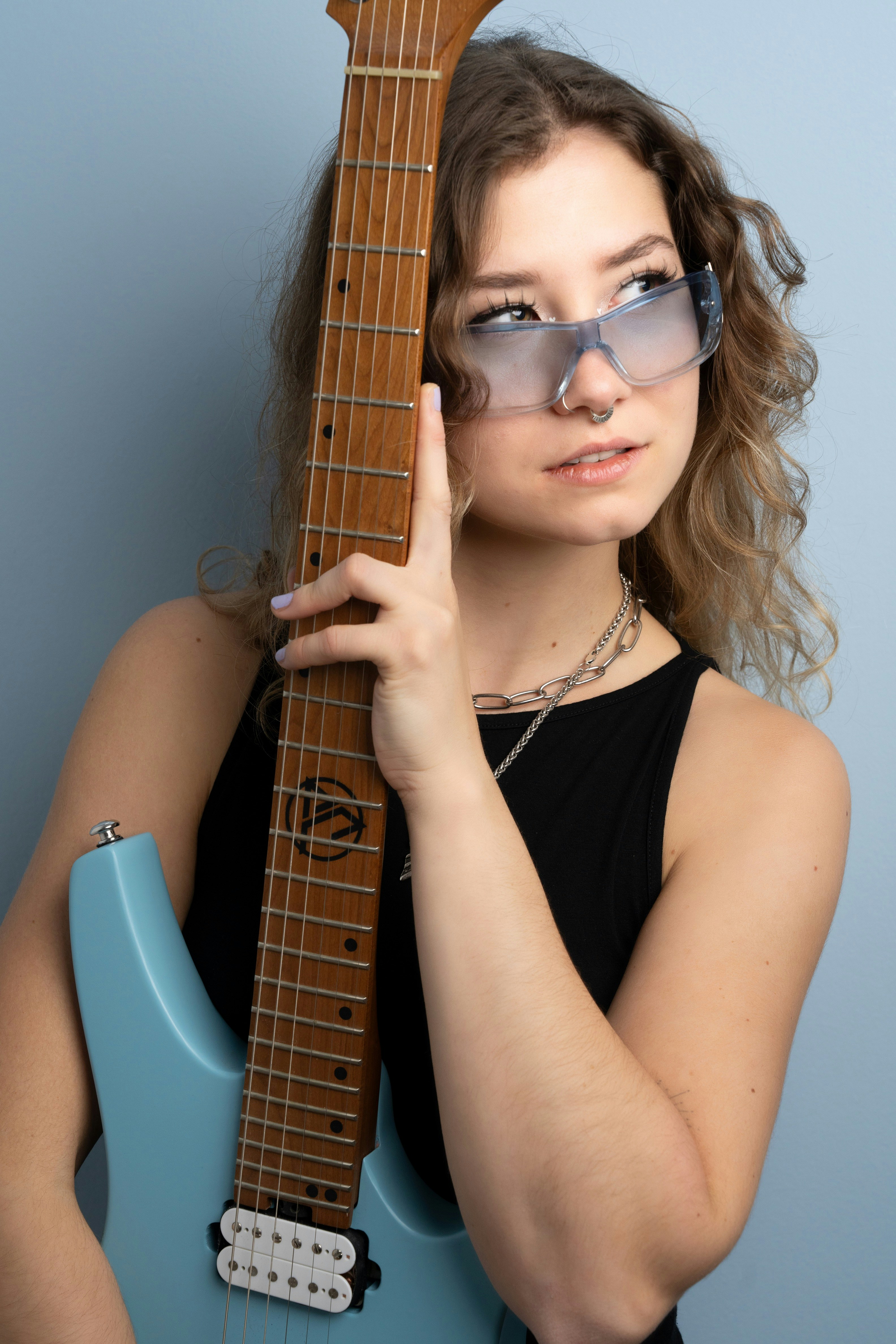 uma mulher usando óculos escuros segurando uma guitarra