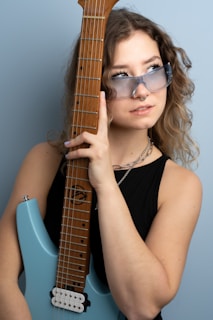 a woman wearing sunglasses holding a guitar