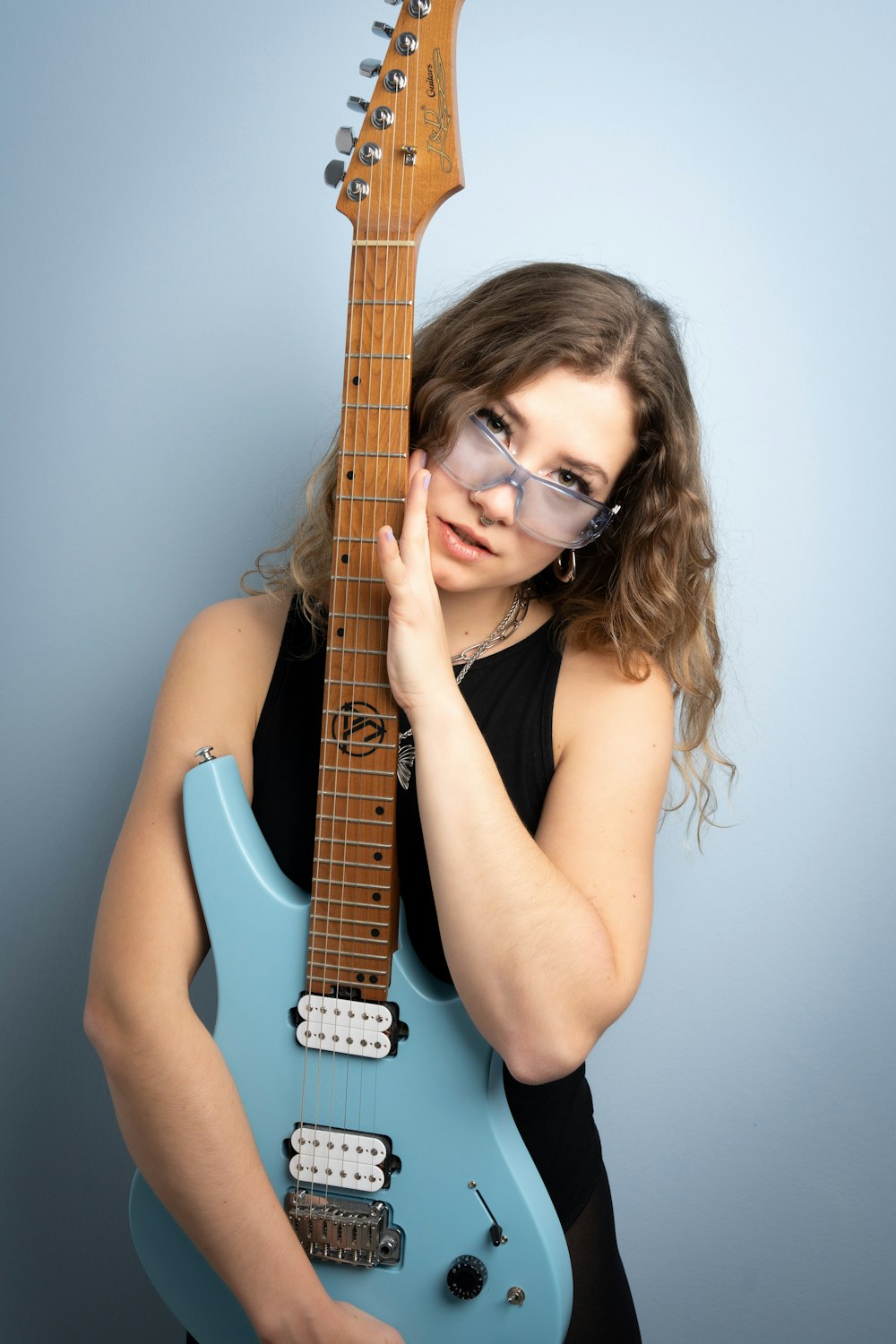 a woman with glasses holding a blue guitar