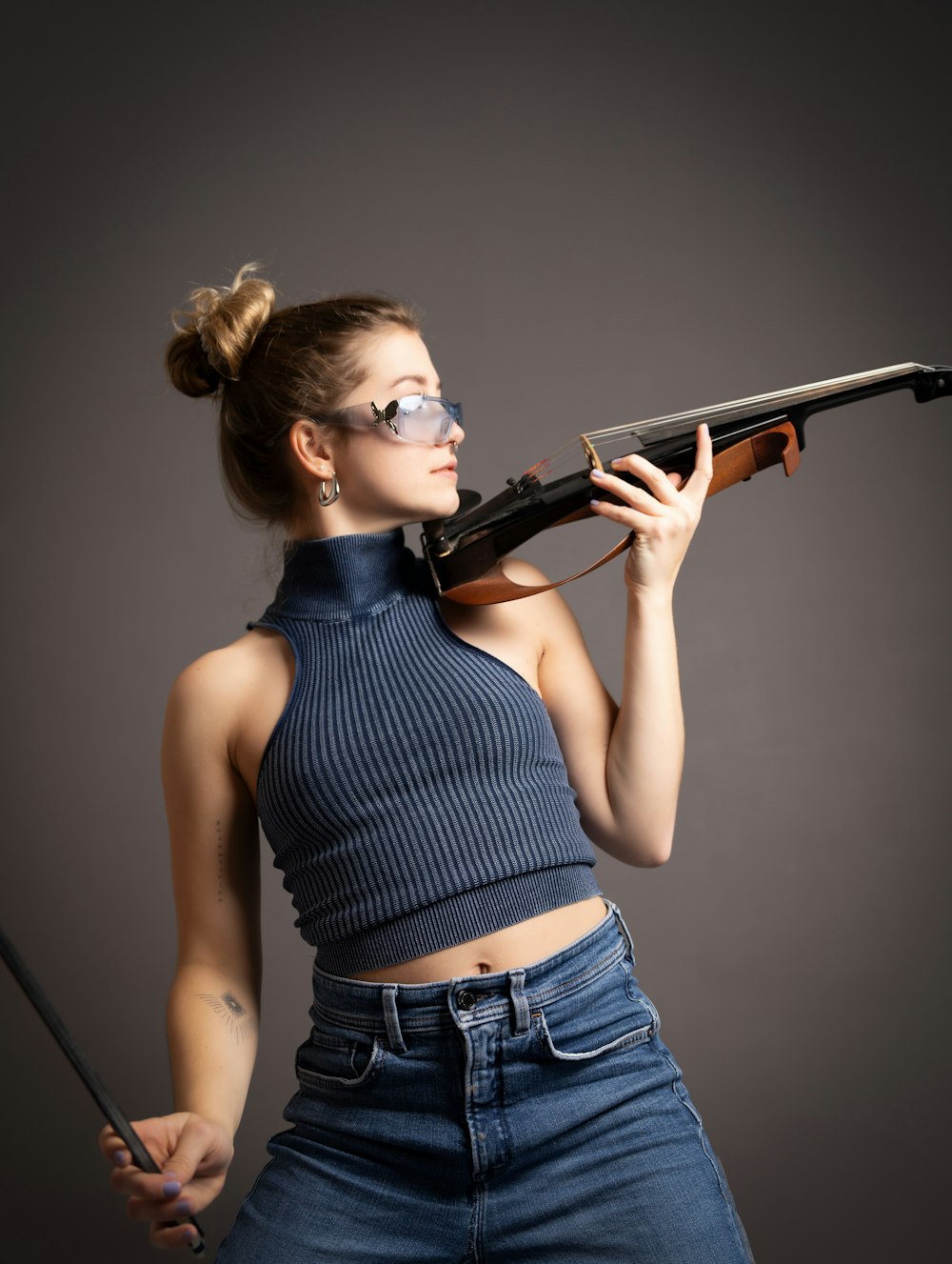 a woman holding a gun and wearing glasses