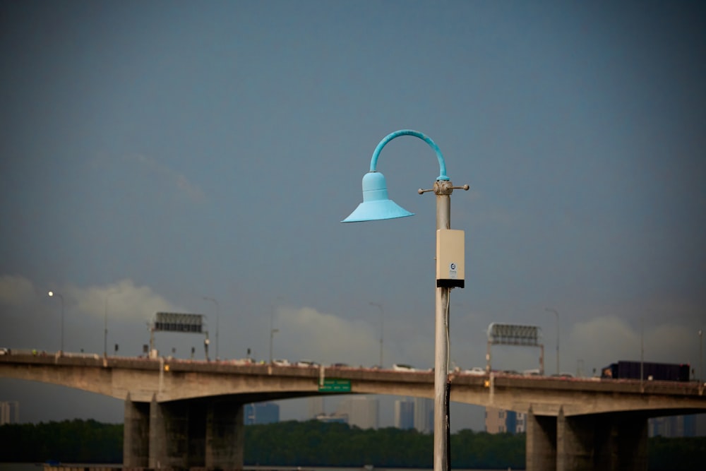 a blue street light sitting on the side of a bridge