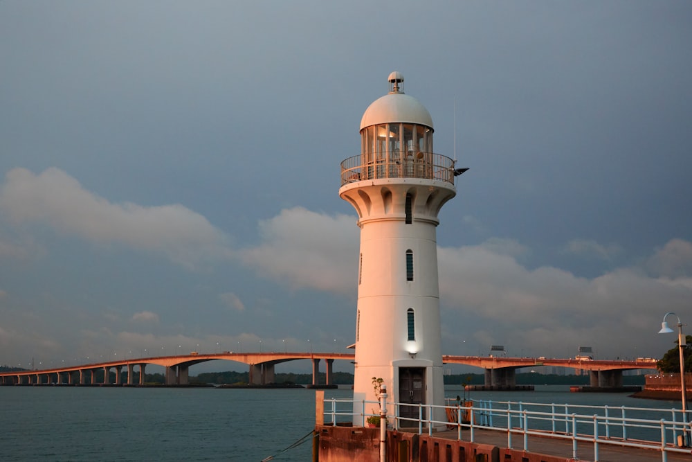 a light house on a pier with a bridge in the background