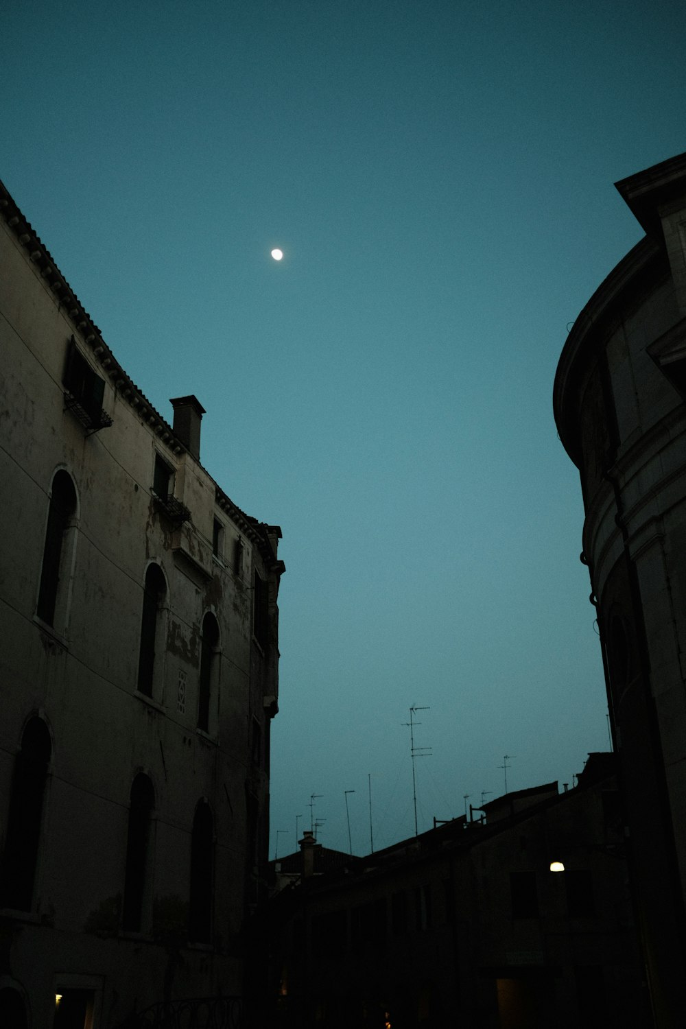 a full moon is seen in the sky above buildings