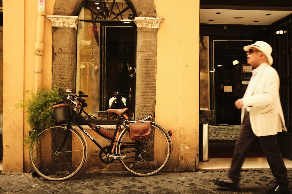 a man walking past a bike parked in front of a building