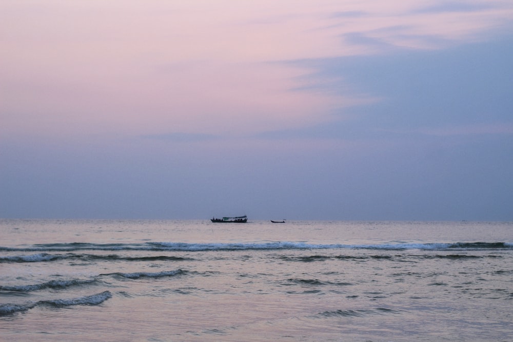 Un bateau est sur l’océan au coucher du soleil