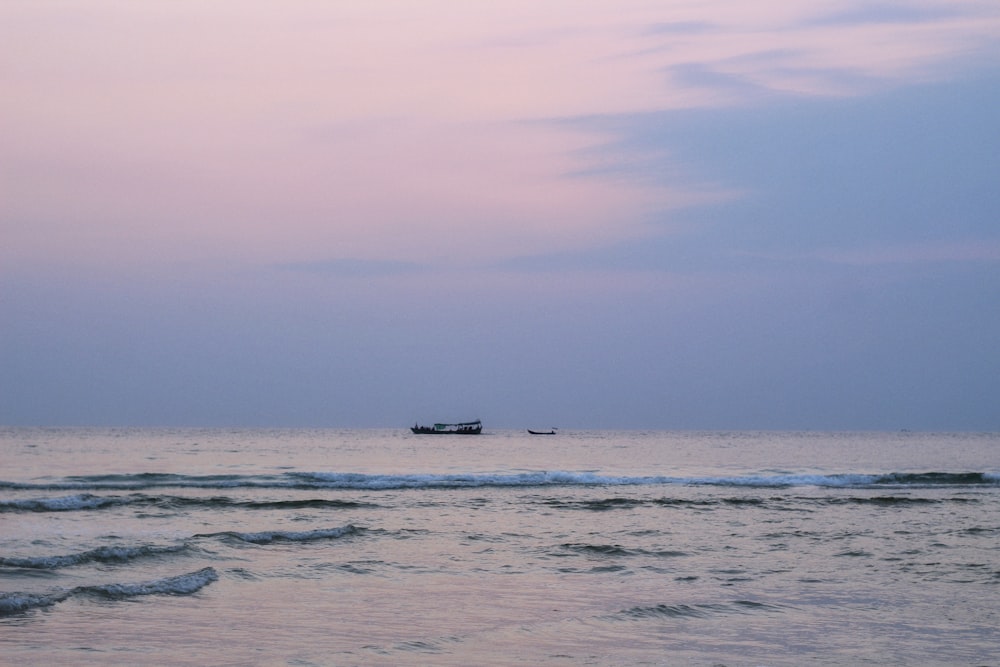 a boat is out on the ocean at sunset