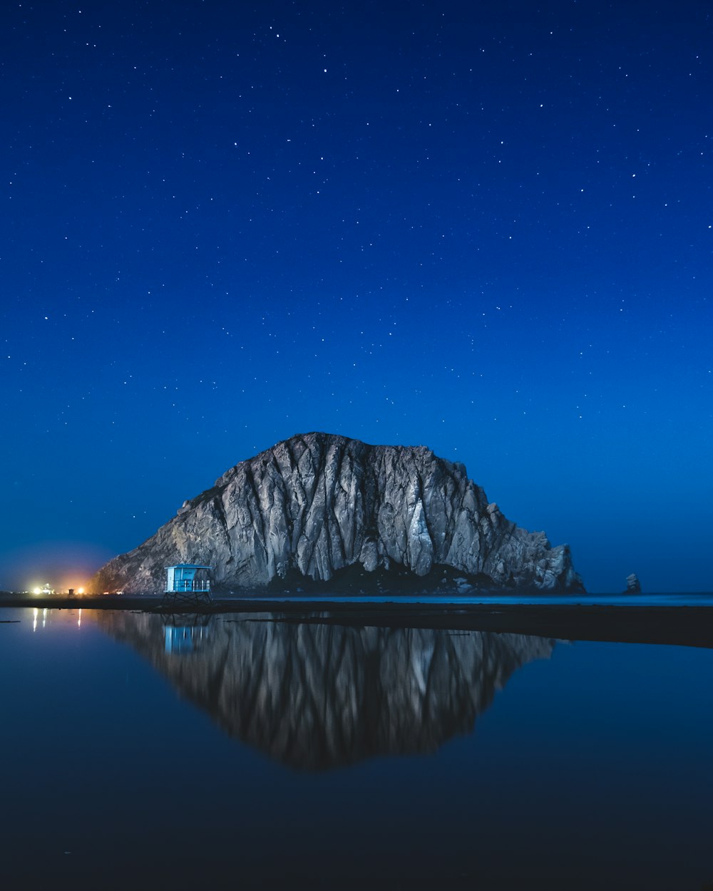 una gran montaña sentada en la cima de un lago bajo un cielo nocturno
