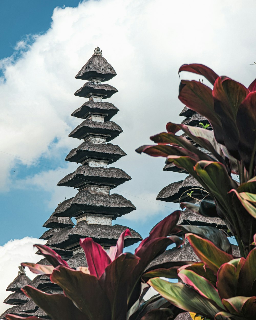 a tall tower made of wooden blocks with plants in front of it