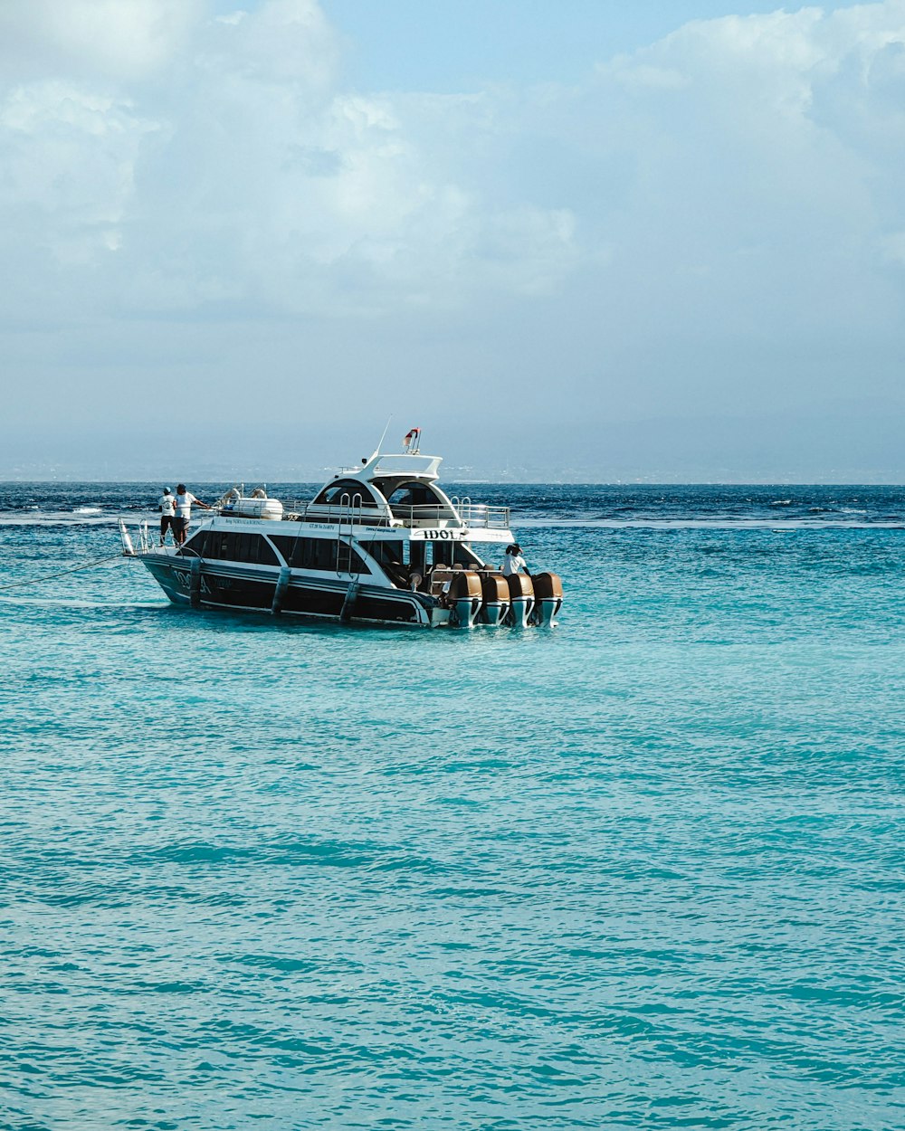 a group of people standing on the back of a boat in the ocean