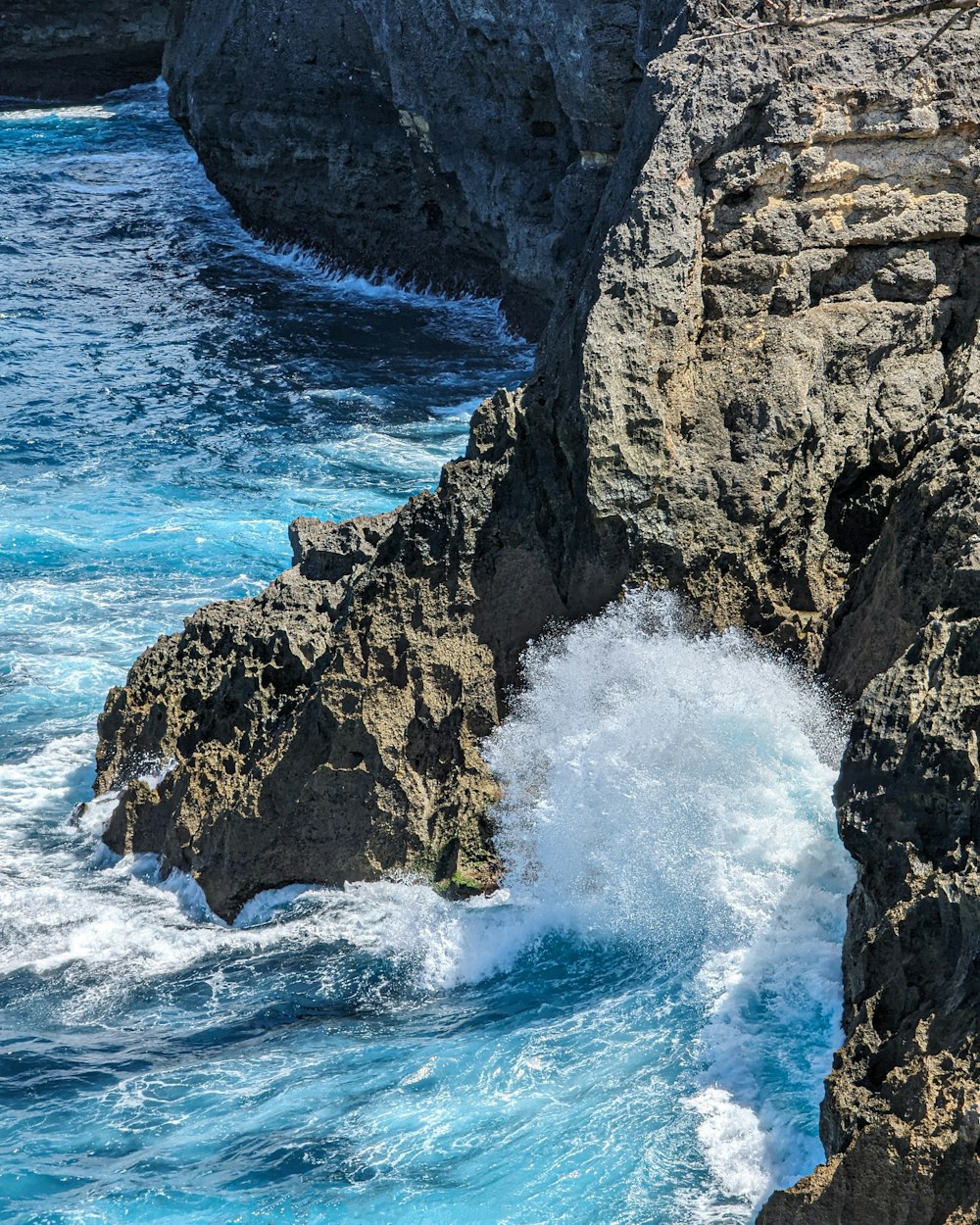 a large wave crashing into the rocks near the ocean