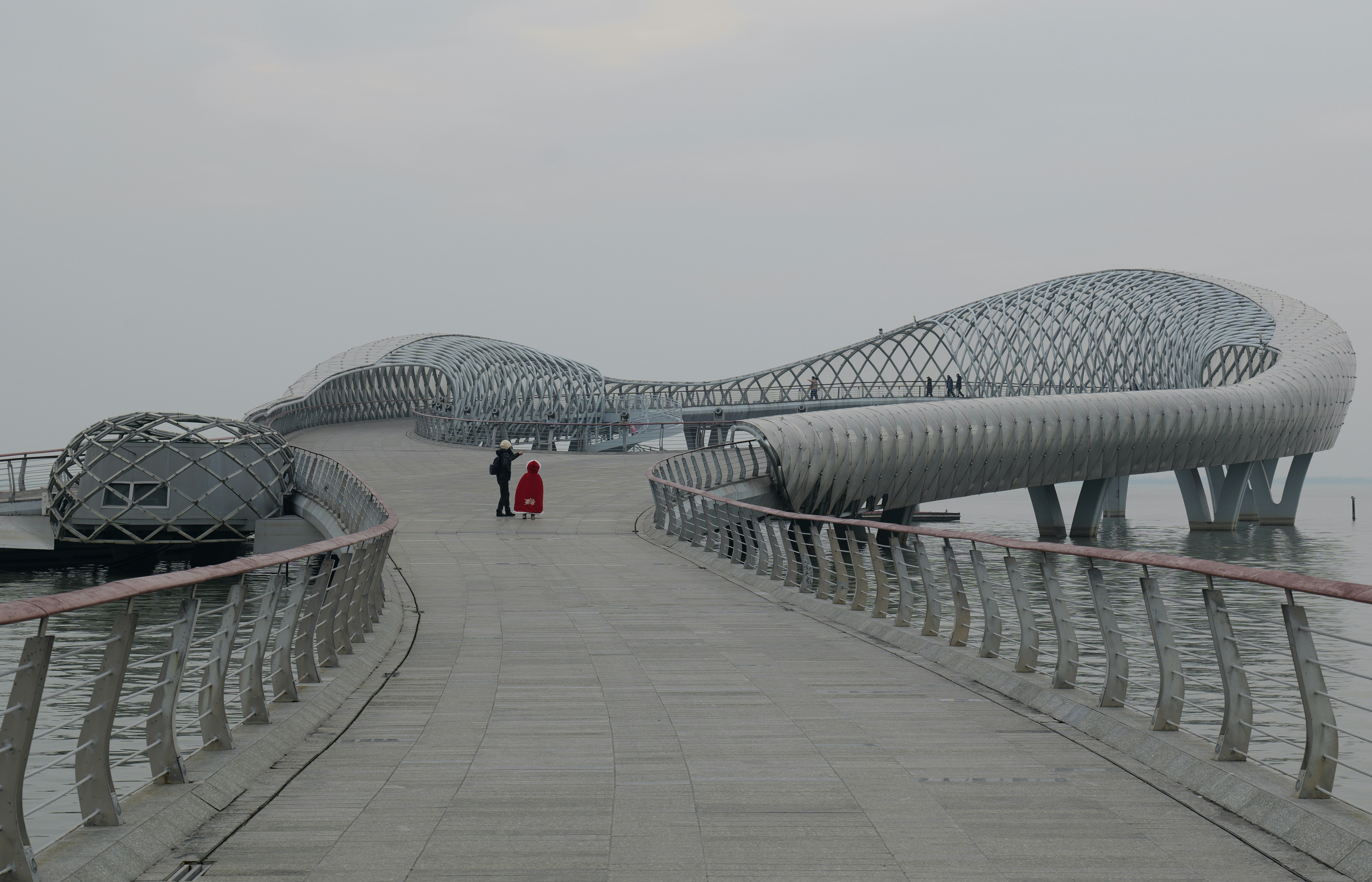 two people walking across a bridge over water