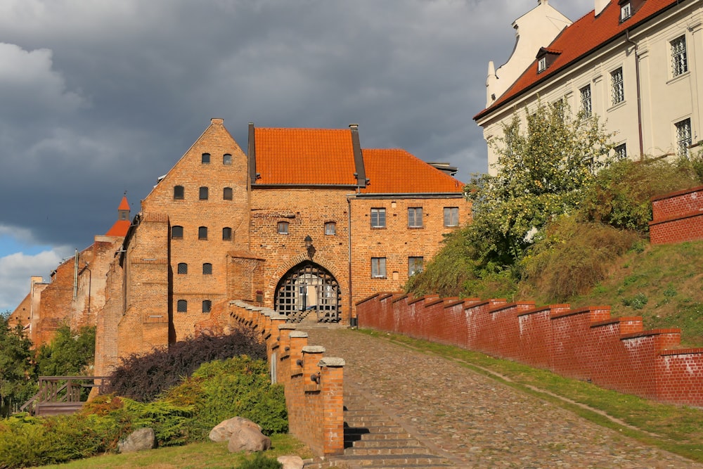 a brick building with a red roof and a stone path leading to it