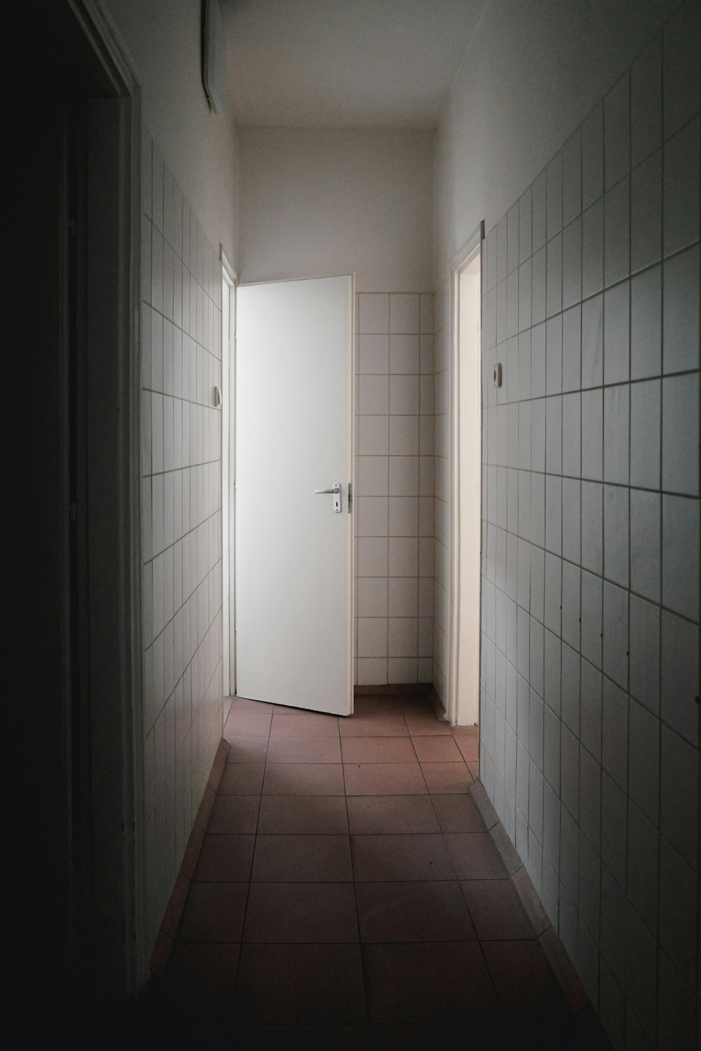 an empty hallway with a door and tiled walls