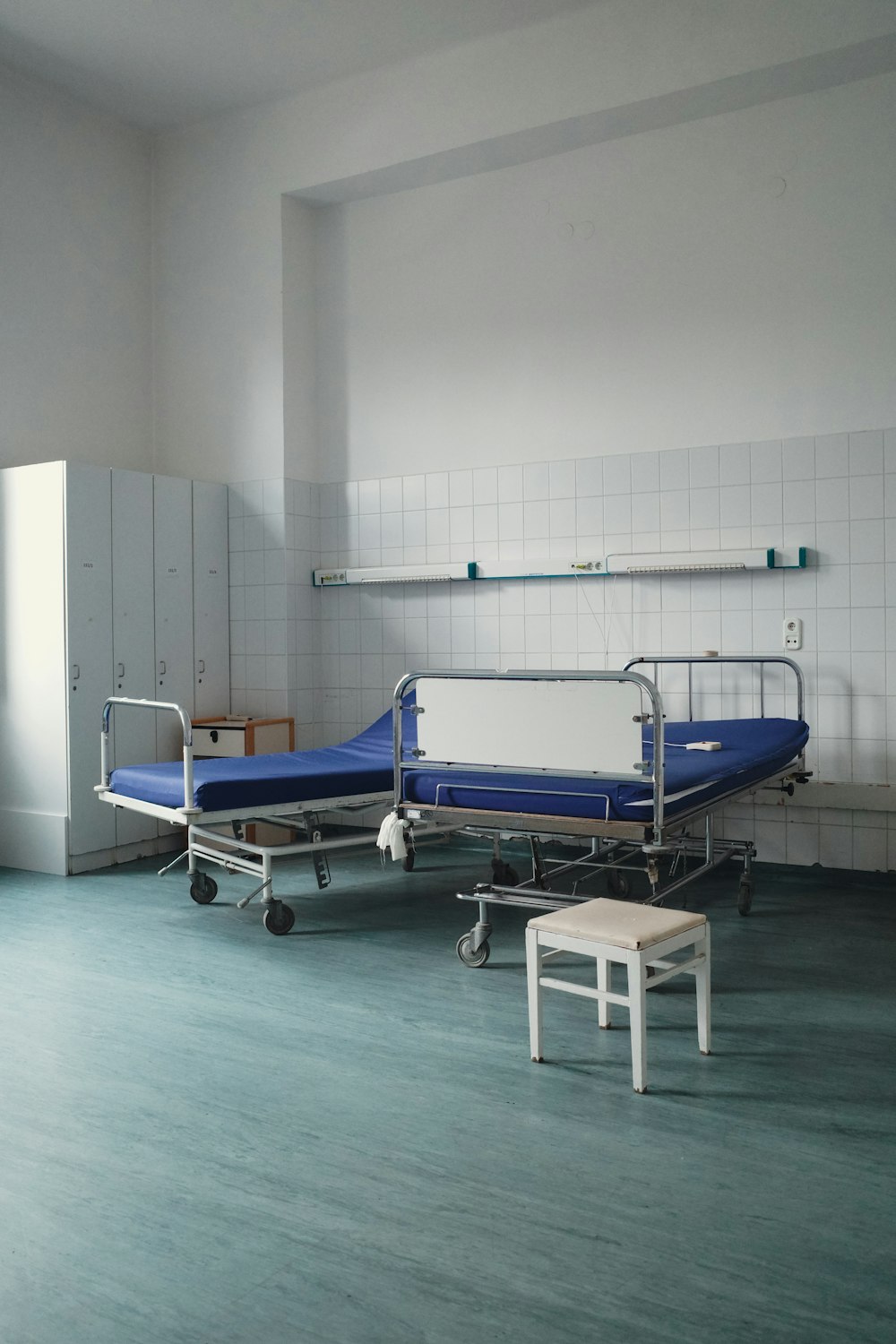 a hospital room with two beds and a stool