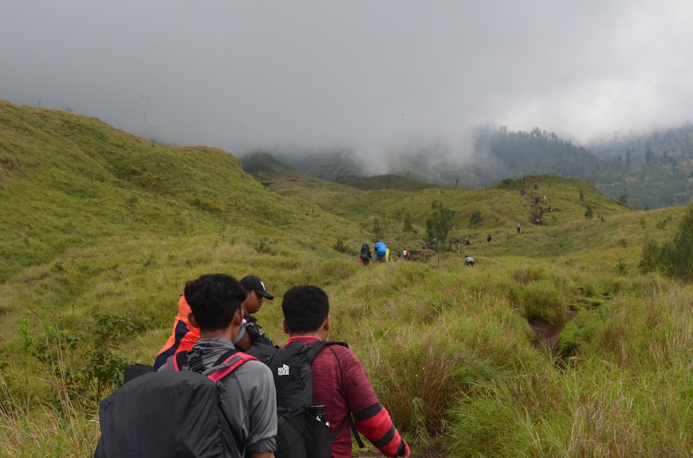 a group of people hiking up a grassy hill