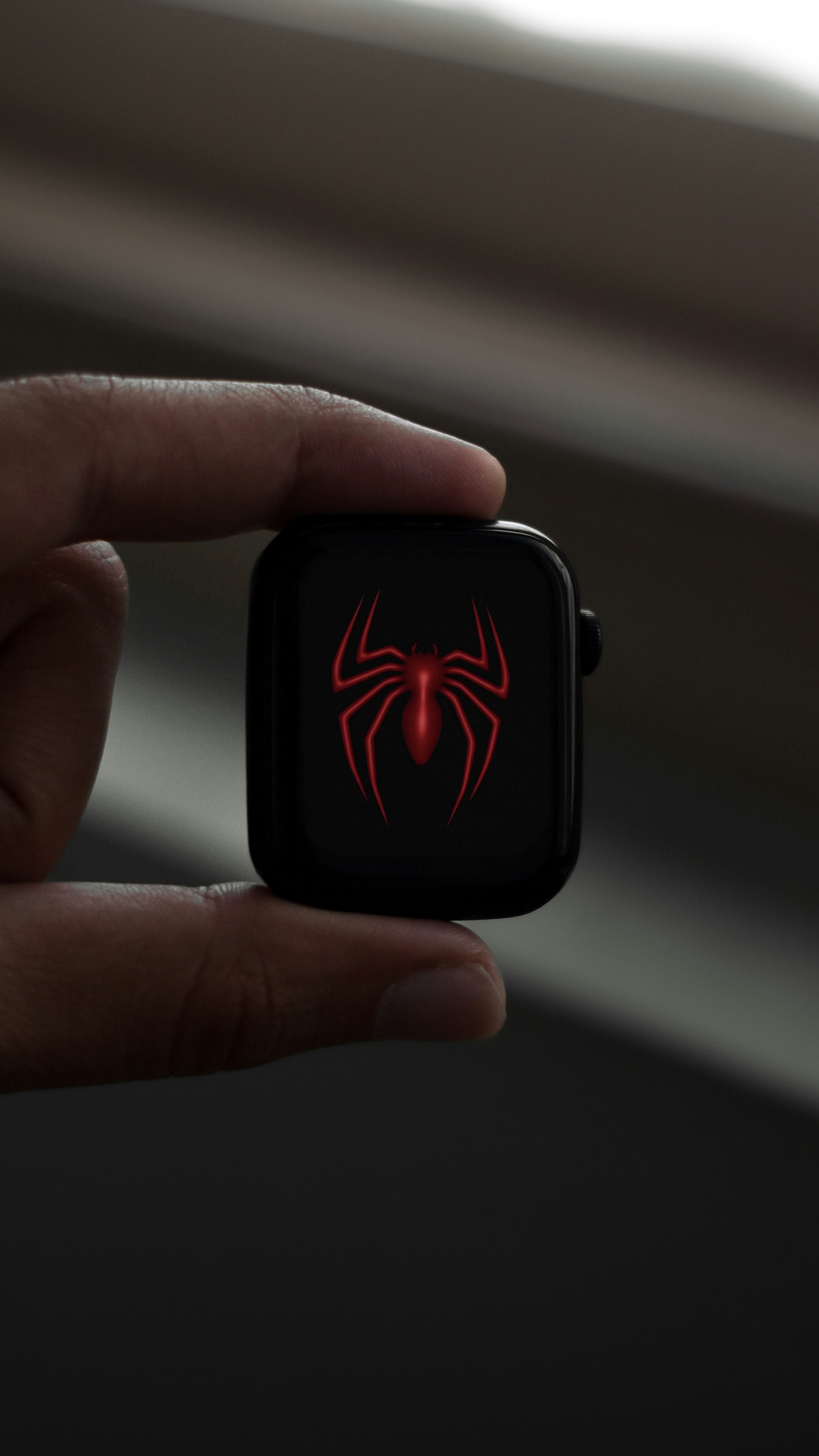a hand holding an apple watch with a spider logo on it