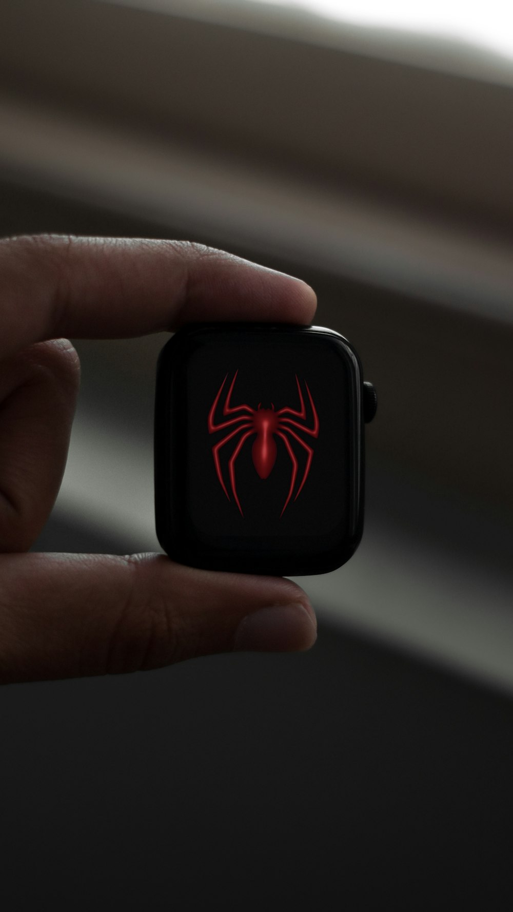 a hand holding an apple watch with a spider logo on it