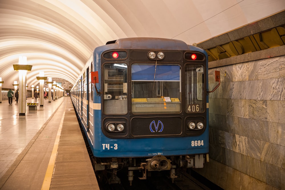 a blue train pulling into a train station