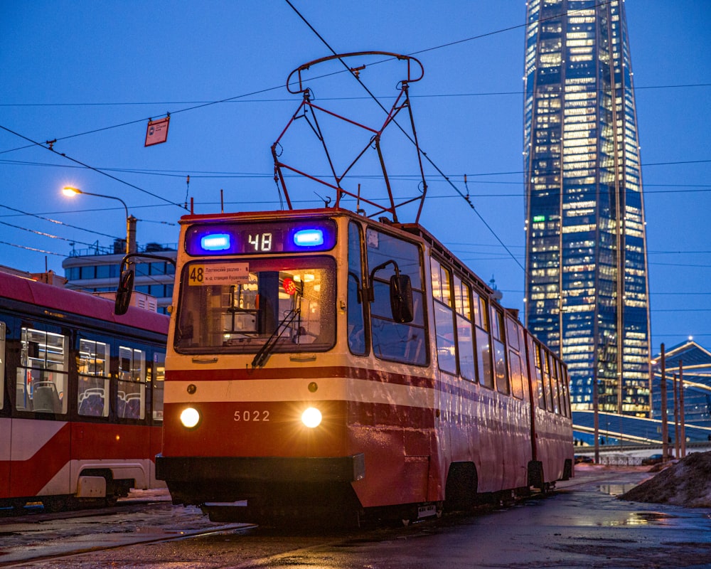 a red and white train traveling past a tall building