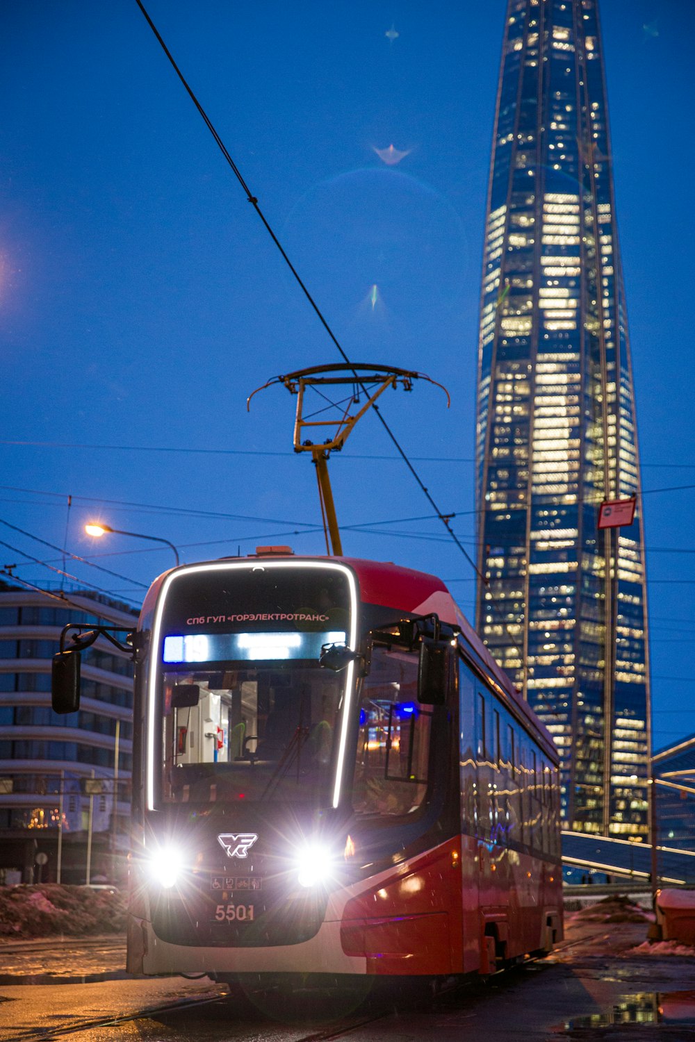 a red and white bus driving down a street next to a tall building