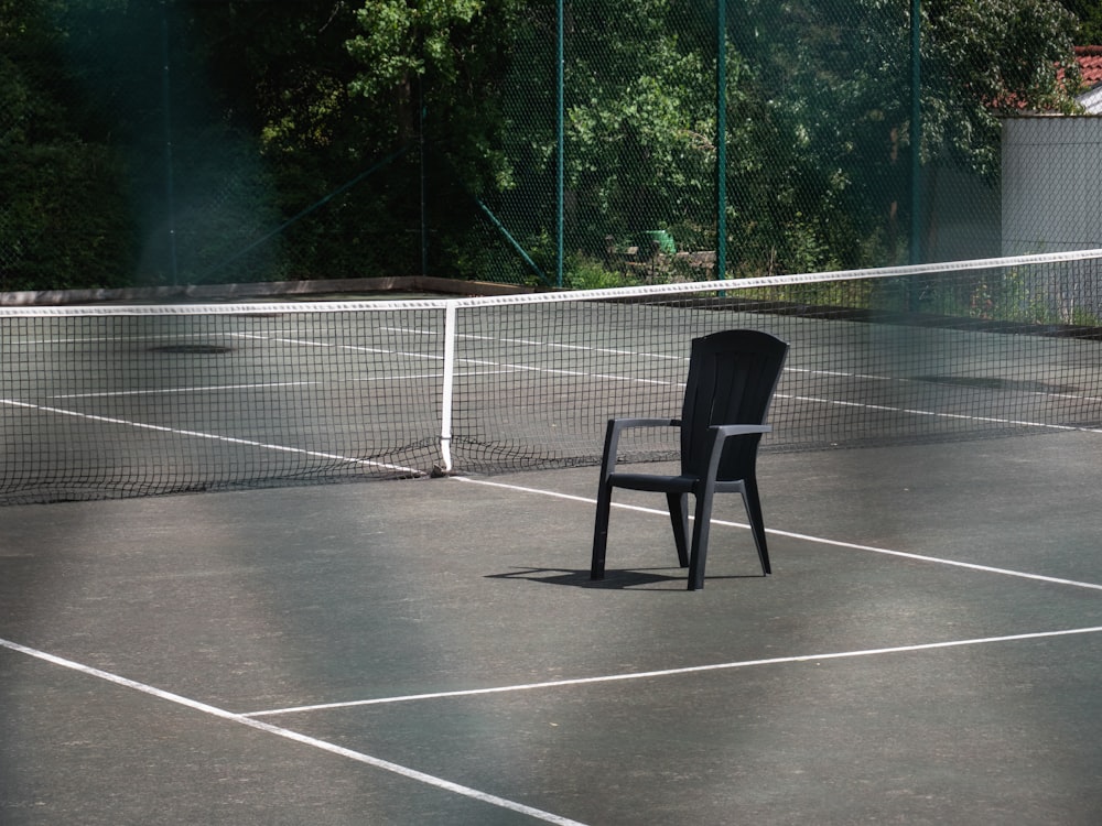 a black chair sitting on top of a tennis court