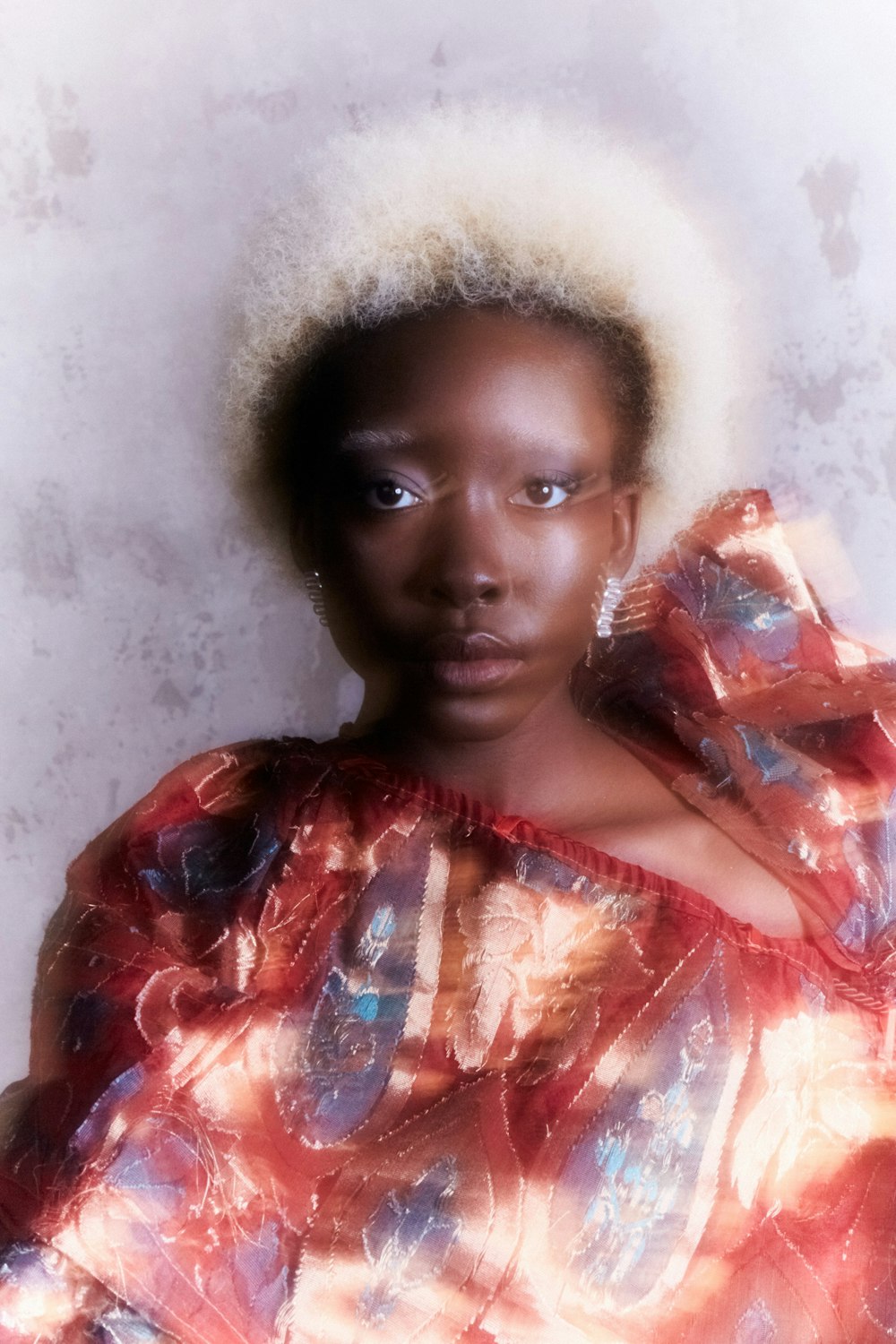 a woman with an afro standing in front of a wall