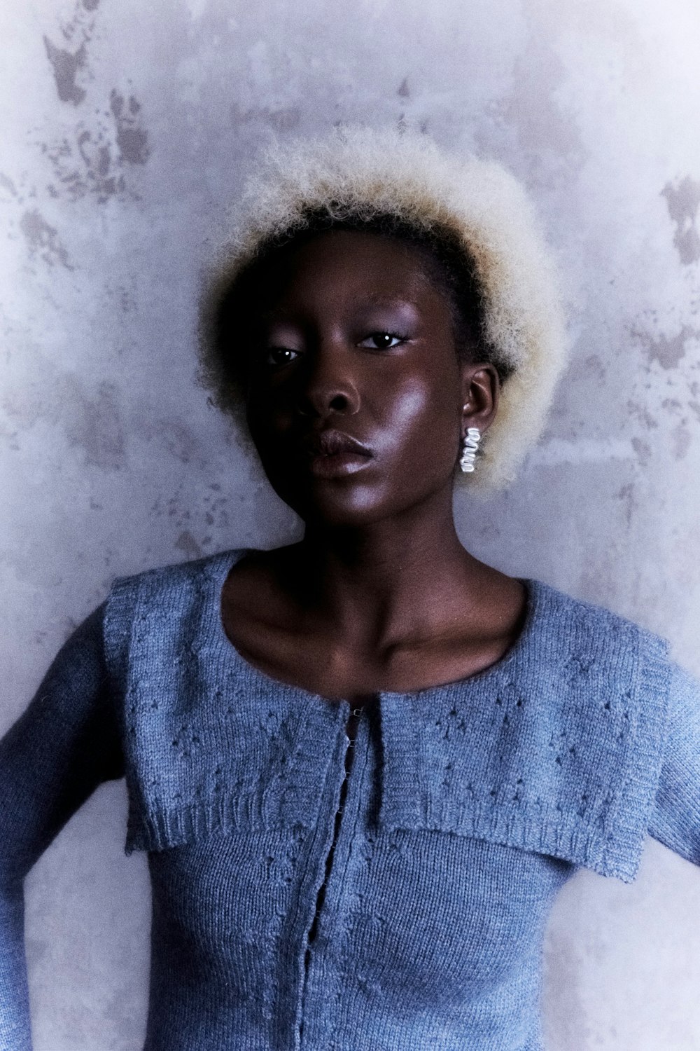 a woman with an afro standing in front of a wall