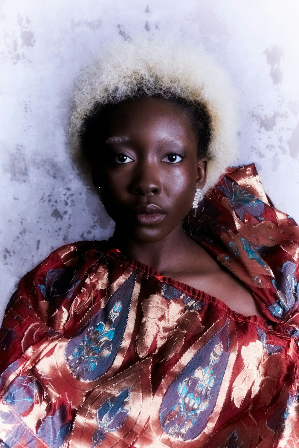 a woman with an afro standing in front of a wall