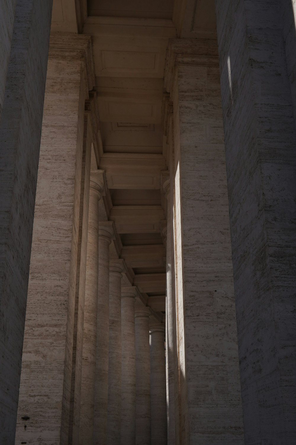 a long hallway with columns and a clock on the wall