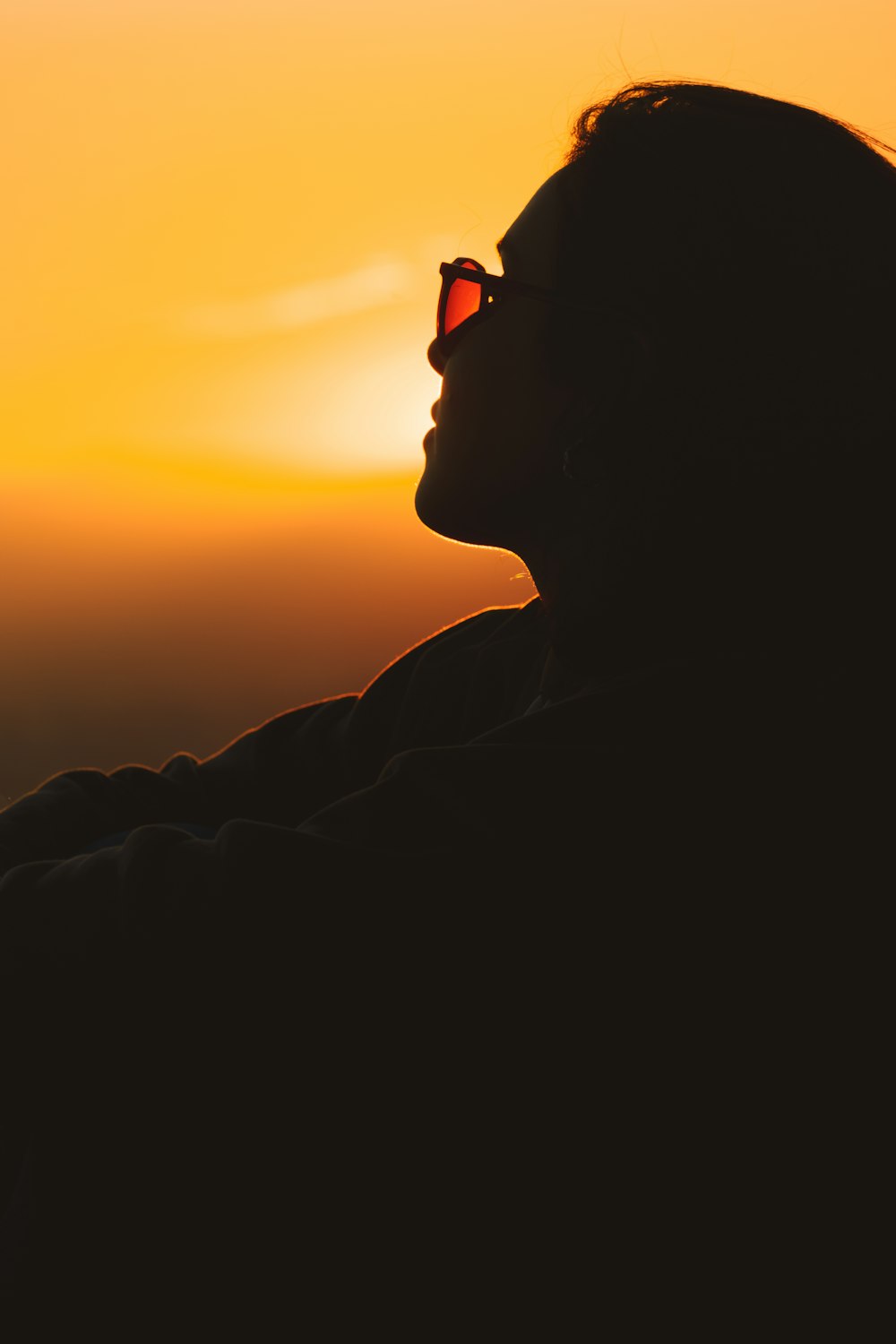 a woman wearing sunglasses looking at the sunset
