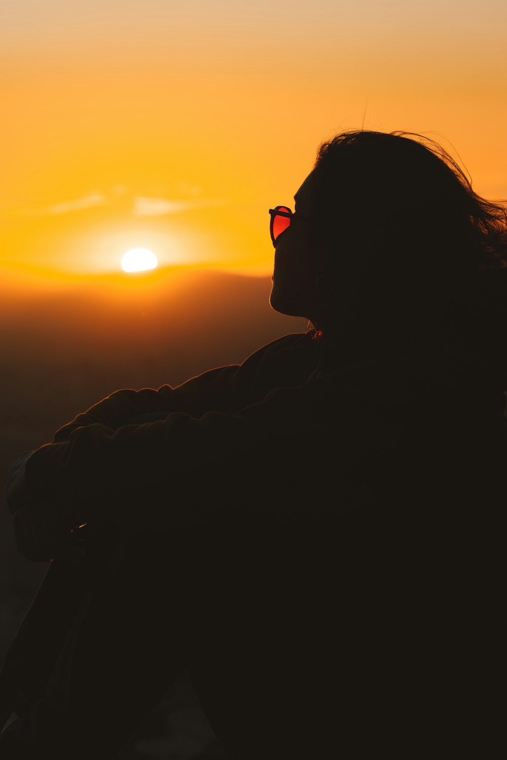 a woman with her hair blowing in the wind at sunset