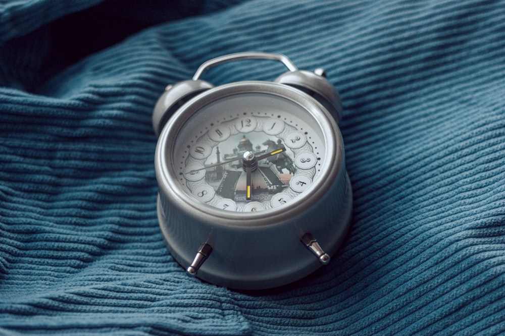 an alarm clock sitting on top of a blue blanket